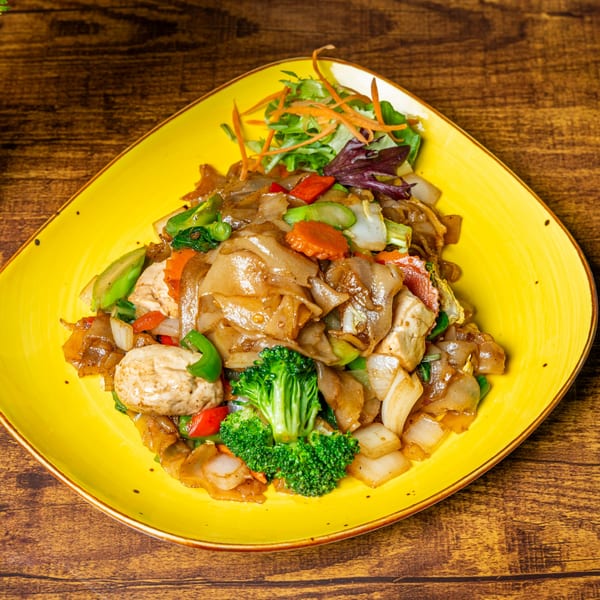 Jaew Thai Cuisine's Pad See Ew with wide noodles, chicken, broccoli, and mixed vegetables on a yellow plate.